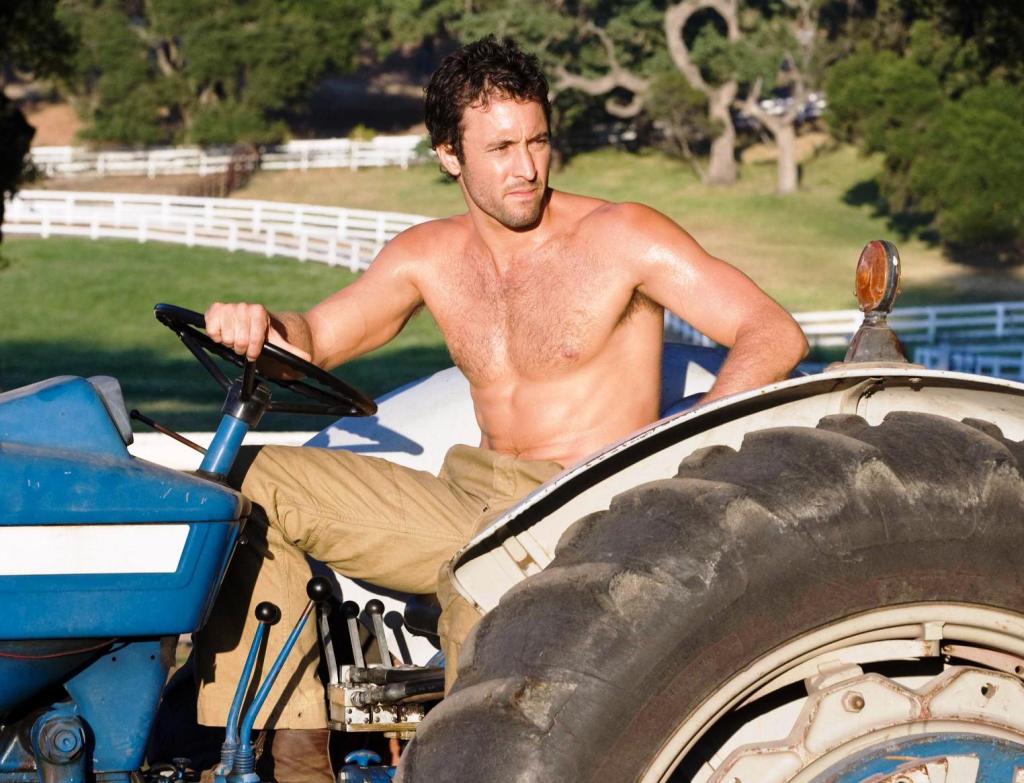 This image has an empty alt attribute; its file name is alex-oloughlin-on-a-tractor-in-the-back-up-plan.jpg